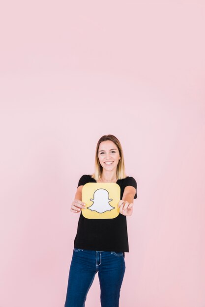 Portret van een lachende jonge vrouw met snapchat pictogram