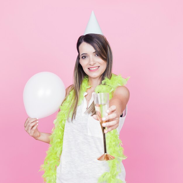 Portret van een lachende jonge vrouw met witte ballon en wijnglas