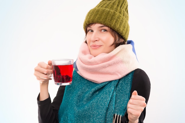 Portret van een lachende vrouw in een wintermuts en sjaal met een kopje in haar hand. virale ziekten concept. gemengde media