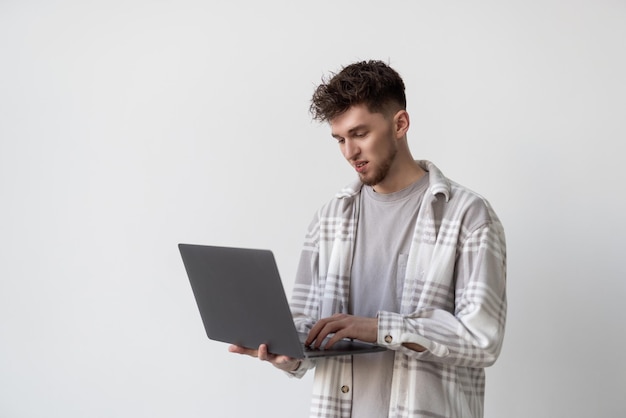 Portret van een man die een laptopcomputer gebruikt over een grijze achtergrond