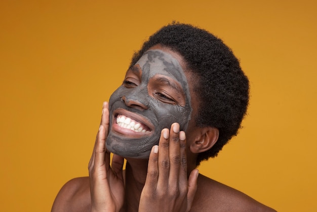 Gratis foto portret van een man die lacht met een houtskoolmasker op zijn gezicht