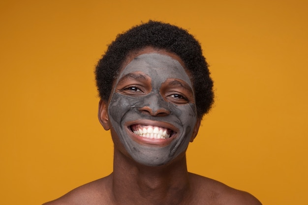 Portret van een man die lacht met een houtskoolmasker op zijn gezicht