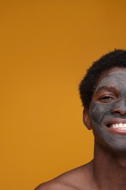 Gratis foto portret van een man die lacht met een houtskoolmasker op zijn gezicht