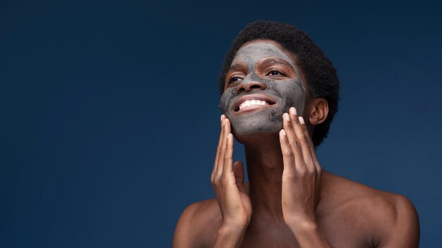 Portret van een man die lacht met een houtskoolmasker op zijn gezicht