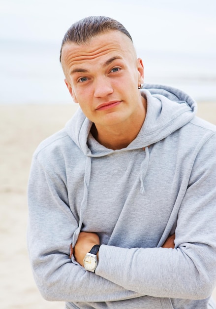 Gratis foto portret van een man die zich voordeed op het strand in een grijze jas