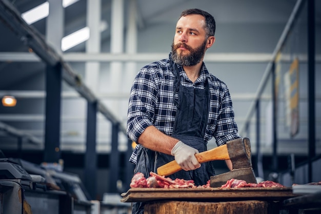 Gratis foto portret van een man met een baard, gekleed in een fleece-shirt, houdt een bijl en vers gesneden vlees vast.