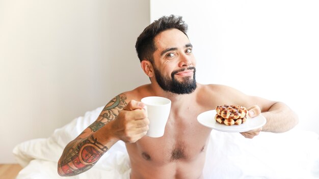 Portret van een man met een kopje koffie en wafel op plaat