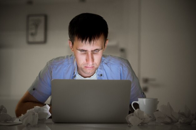 Portret van een man met een laptop, 's avonds laat, schermlicht