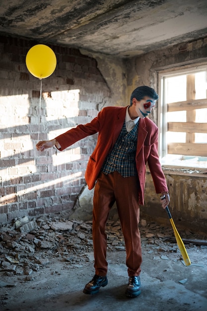 Gratis foto portret van een man met enge clownmake-up en ballon