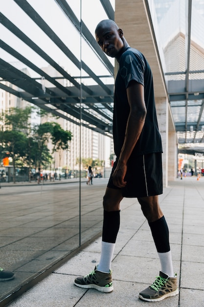 Gratis foto portret van een mannelijke atleet loper staande voor reflecterend glas