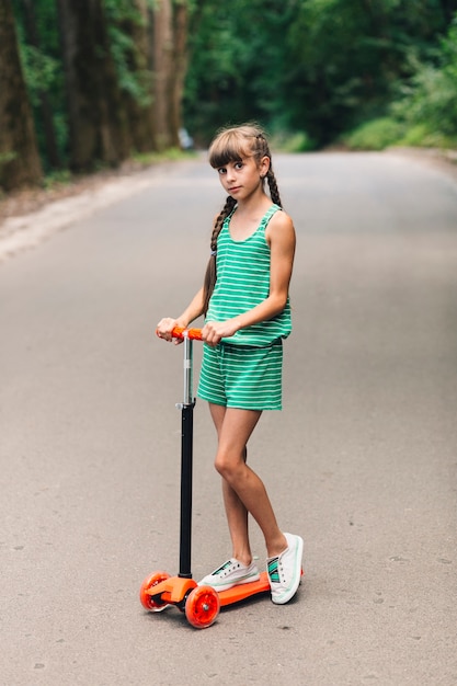 Portret van een meisje dat zich op duwautoped bij straat bevindt