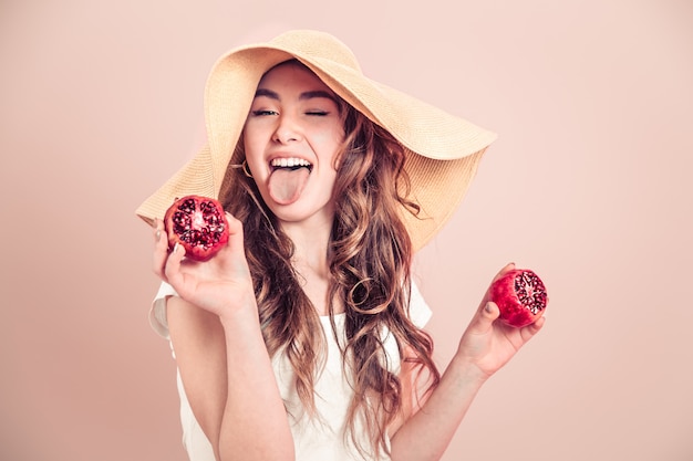 Portret van een meisje in een zomer hoed met fruit op een gekleurde muur