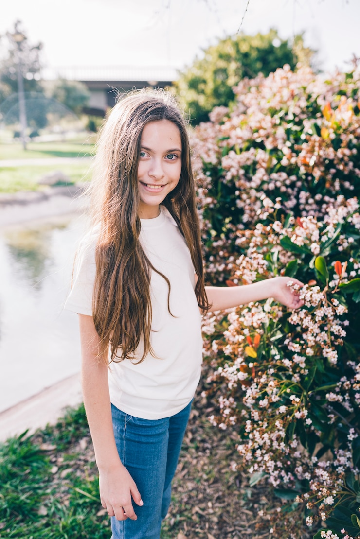 Gratis Foto portret van een meisje met bloemen op plant in park