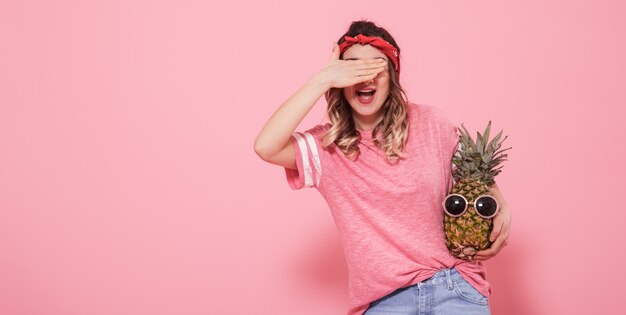 Portret van een meisje met een gesloten oog op een roze achtergrond
