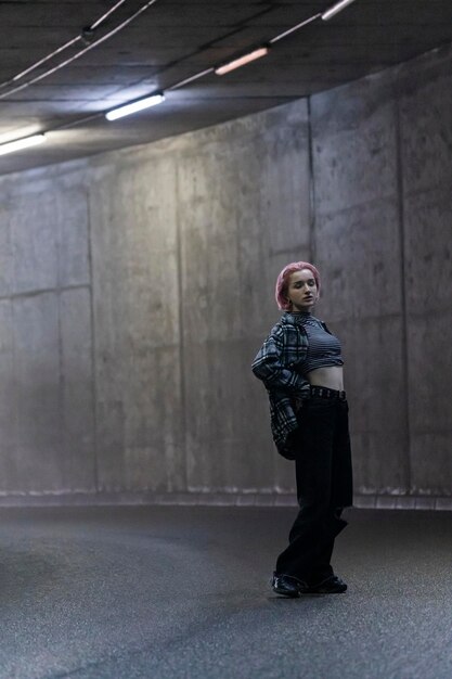 Portret van een meisje met roze haren dat bij de tunnel staat en naar de camera kijkt