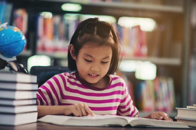 Portret van een meisje van het studentenkind die bij bibliotheek bestuderen