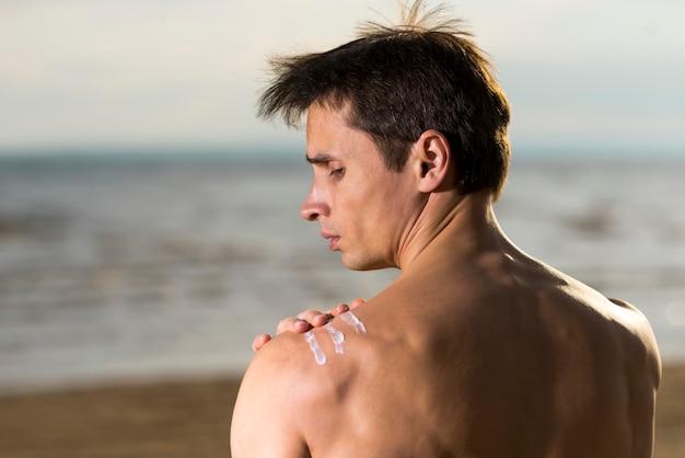 Portret van een mens die zonneschermlotion toepast