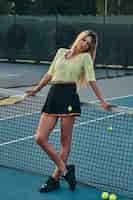 Gratis foto portret van een mooi blond meisje, dat poseert voor de fotograaf op de tennisbaan.