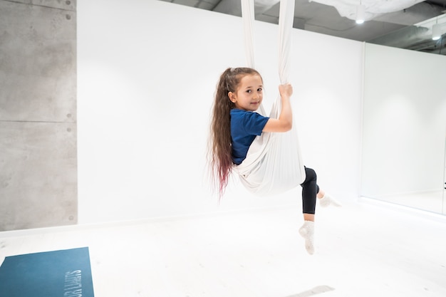 Portret van een mooi jong meisje die zich bezighouden met vlieg yoga op doeken.
