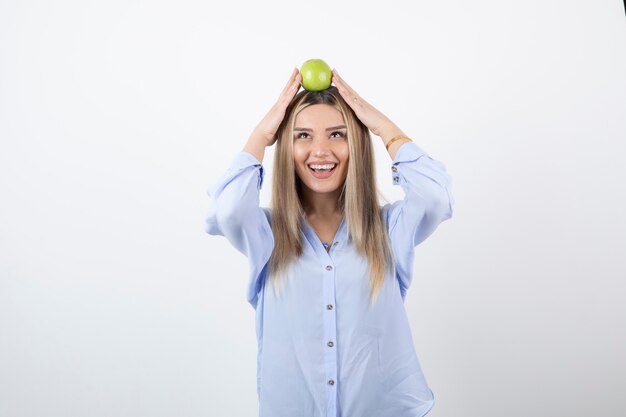 portret van een mooi meisjesmodel dat staat en een groene verse appel vasthoudt.