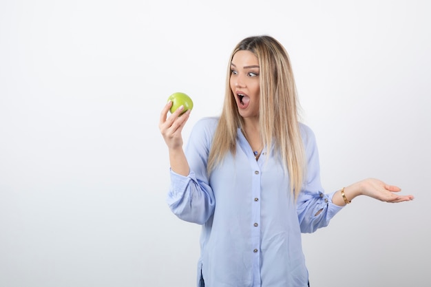 portret van een mooi meisjesmodel dat staat en een groene verse appel vasthoudt.