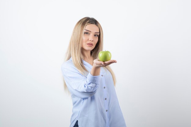 portret van een mooi meisjesmodel dat staat en een groene verse appel vasthoudt.