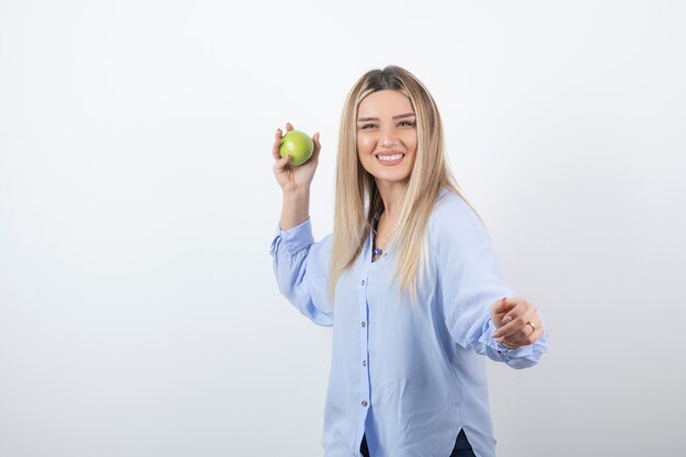 portret van een mooi meisjesmodel dat staat en een groene verse appel vasthoudt.