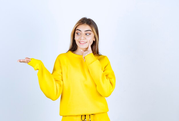 Portret van een mooi vrouwenmodel dat staat en poseert in een geel t-shirt