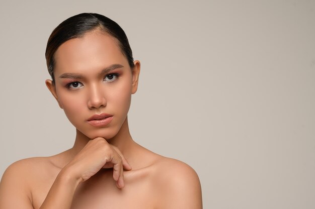 Portret van een mooie aziatische vrouw raakt de kin aan met een mooie, natuurlijke, schone huid, make-up van de natuur