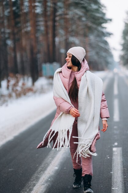 Portret van een mooie blanke vrouw op een weg door besneeuwde bossen