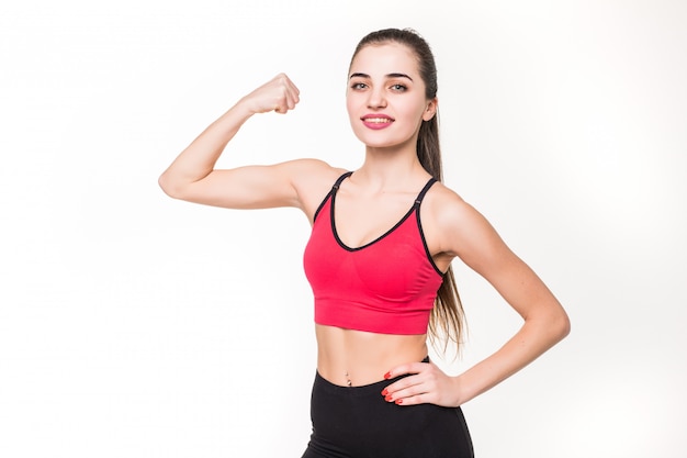 Portret van een mooie geschiktheidsvrouw die haar bicepsen op een witte muur toont