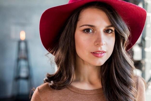 Portret van een mooie jonge vrouw met roze hoed op haar hoofd camera kijken