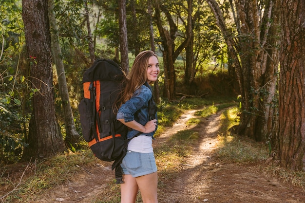 Portret van een mooie jonge vrouw met rugzak die zich in bos bevindt