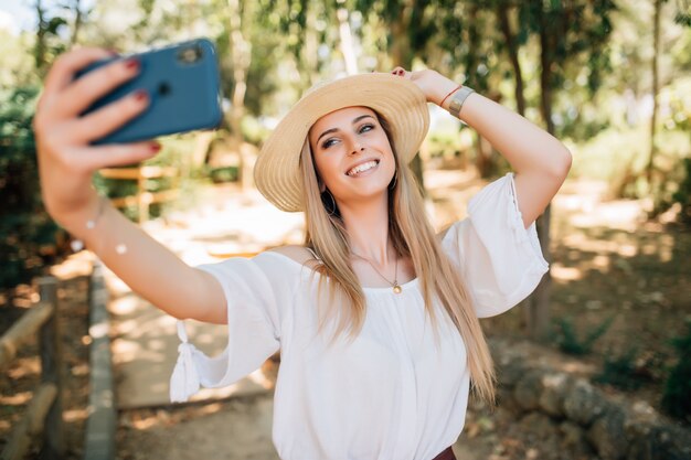 Portret van een mooie jonge vrouw selfie in het park met een smartphone