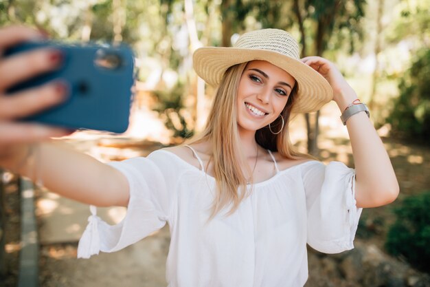 Portret van een mooie jonge vrouw selfie in het park met een smartphone
