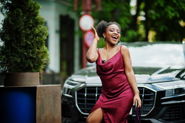 Portret van een mooie natuurlijke jonge Afrikaanse vrouw met afrohaar Zwart model in rode zijden jurk