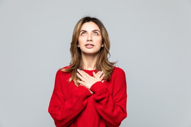 Portret van een mooie vrouw gekleed in rode trui geïsoleerd over grijze muur