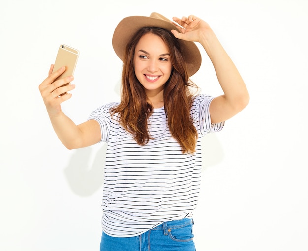 Portret van een mooie vrouw in de zomer hipster kleren die een selfie nemen op witte muur wordt geïsoleerd