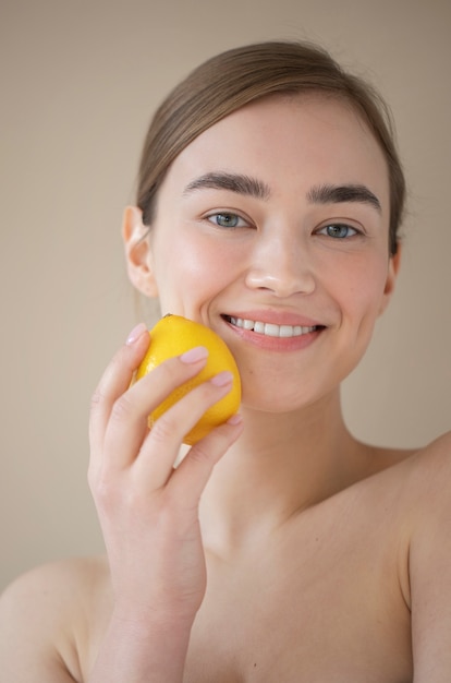 Gratis foto portret van een mooie vrouw met een heldere huid die citroenfruit vasthoudt