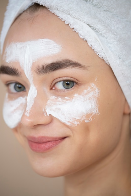 Portret van een mooie vrouw met een heldere huid die een vochtinbrengende crème op haar gezicht gebruikt