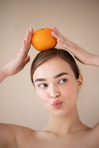 Portret van een mooie vrouw met een heldere huid die oranje fruit vasthoudt
