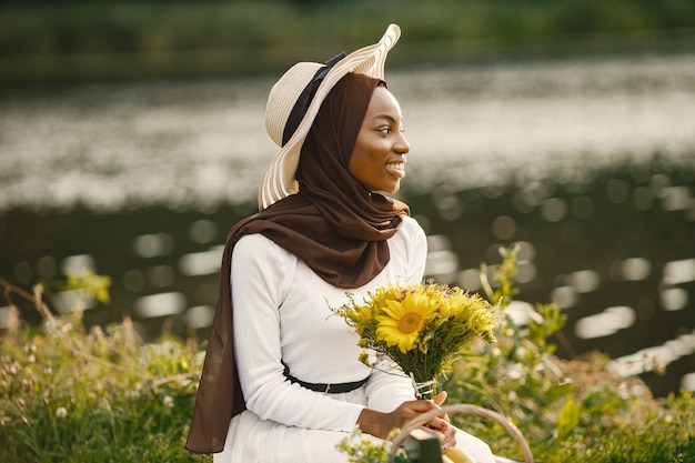 Portret van een moslimvrouw zit op de geruite picknickdeken bij de rivier