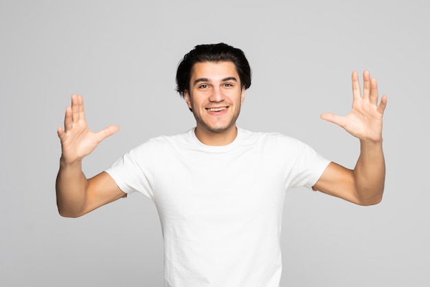 Portret van een opgewonden casual man die met opgeheven handen op wit staat