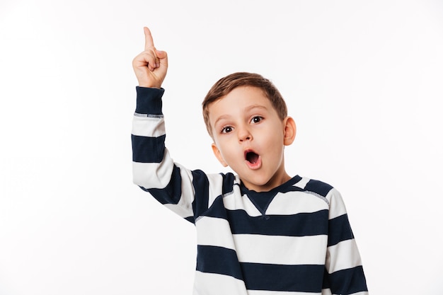 Portret van een opgewonden slimme kleine jongen die vinger omhoog wijst