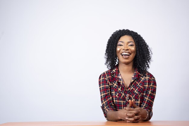 Portret van een opgewonden vrij jonge zwarte vrouw die aan een bureau zit