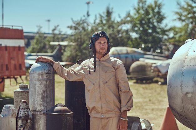 Gratis foto portret van een piloot in uniform en vliegende helm in de buurt van bommen voor een bommenwerpervliegtuig in een openluchtmuseum.