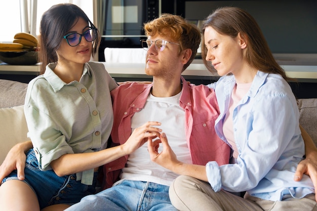 Portret van een polyamorous stel dat thuis op de bank zit