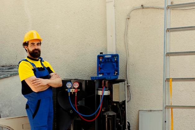 Gratis foto portret van een professionele ingenieur die voor een vaste airconditioner staat, trots op het geleverde werk. bekwame technicus gecontracteerd door de klant die tevreden is met het soepele onderhoud van de hvac-systeemcomponenten