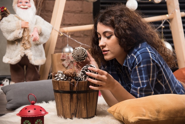 Portret van een schattige jonge vrouw die in een houten mand met dennenappels kijkt