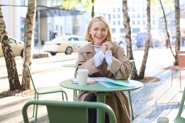 Gratis foto portret van een schattige jonge vrouwelijke student die voor het examen herziet in een café en koffie drinkt en studeert